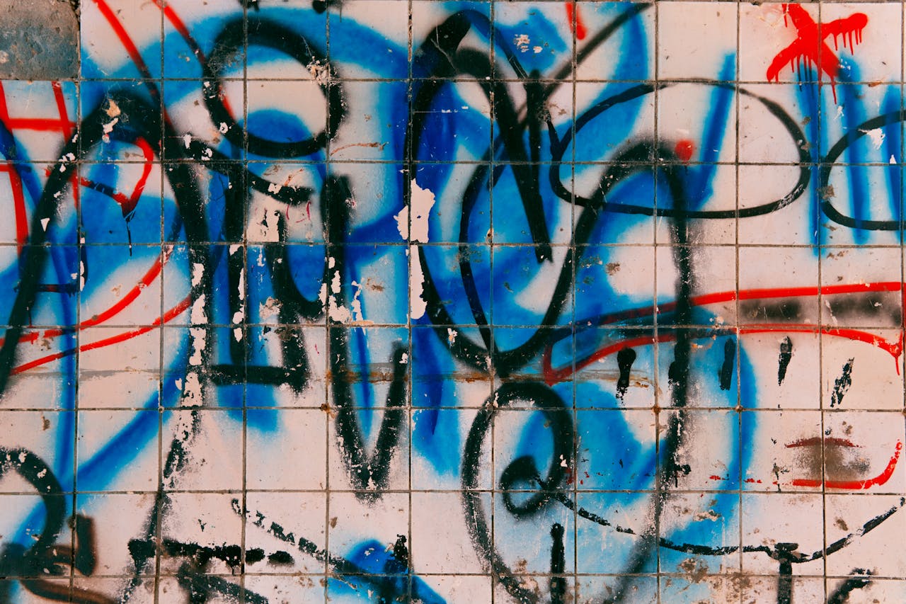 Weathered multicolored graffiti on wall of modern building covered with tile on daytime